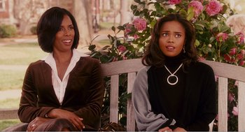 Movie still from “Why Did I Get Married?” (2007), directed by Tyler Perry – Two women sitting on a wooden bench in front of a bush; Medium shot, Over the shoulder angle