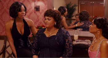 Movie still from “Why Did I Get Married?” (2007), directed by Tyler Perry – A woman in a black dress standing next to a table; Medium shot, Over the shoulder angle