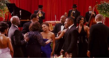 Movie still from “Why Did I Get Married?” (2007), directed by Tyler Perry – A group of people standing around a table; Wide shot, Over the shoulder angle