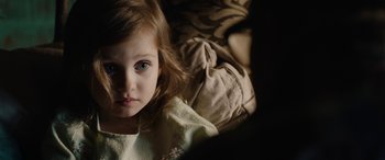 Movie still from “Wildling” (2018), directed by Fritz Böhm – A little girl laying on a bed looking at the camera; Close Up shot, High angle