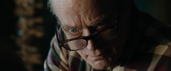 Movie still from “Wildling” (2018), directed by Fritz Böhm – An older man wearing glasses looking at the camera; Close Up shot, Over the shoulder angle