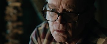 Movie still from “Wildling” (2018), directed by Fritz Böhm – An older man wearing glasses looking at the camera; Close Up shot, Over the shoulder angle