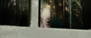 Movie still from “Wildling” (2018), directed by Fritz Böhm – A woman's face is seen through a window; Extreme Close Up shot, Over the shoulder angle