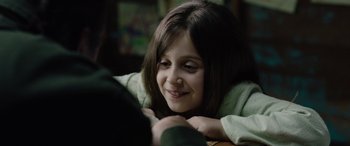 Movie still from “Wildling” (2018), directed by Fritz Böhm – A young girl smiles as she looks at the camera; Close Up shot, Over the shoulder angle