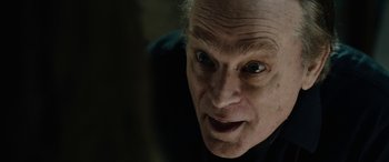Movie still from “Wildling” (2018), directed by Fritz Böhm – An old man with a strange look on his face; Close Up shot, Over the shoulder angle