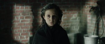Movie still from “Wildling” (2018), directed by Fritz Böhm – A young girl is wrapped in a black blanket; Close Up shot, Over the shoulder angle