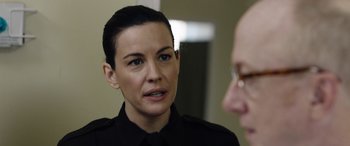 Movie still from “Wildling” (2018), directed by Fritz Böhm – A woman wearing a black uniform talking to a man; Close Up shot, Over the shoulder angle