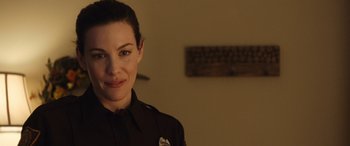 Movie still from “Wildling” (2018), directed by Fritz Böhm – A woman in a police uniform smiling for the camera; Close Up shot, Over the shoulder angle