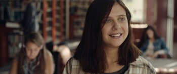 Movie still from “Wildling” (2018), directed by Fritz Böhm – A young woman with long black hair smiles for the camera; Close Up shot, Over the shoulder angle