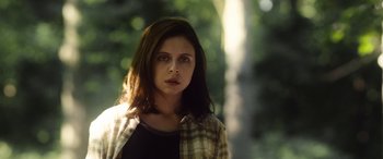 Movie still from “Wildling” (2018), directed by Fritz Böhm – A young woman in a plaid shirt in a forest; Close Up shot, Low angle