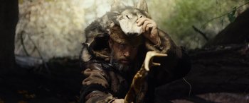 Movie still from “Wildling” (2018), directed by Fritz Böhm – A man in a fur coat with a wolf on his head; Medium shot, Over the shoulder angle