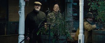 Movie still from “Wildling” (2018), directed by Fritz Böhm – Two men standing next to each other in front of some plants; Medium shot, Low angle