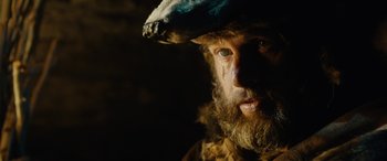 Movie still from “Wildling” (2018), directed by Fritz Böhm – A man with a beard wearing a hat; Close Up shot, Low angle