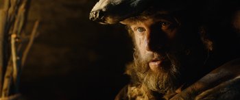 Movie still from “Wildling” (2018), directed by Fritz Böhm – A man with a beard and a hat on; Close Up shot, Low angle