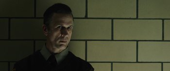 Movie still from “Wildling” (2018), directed by Fritz Böhm – A man standing in front of a brick wall; Close Up shot, Low angle