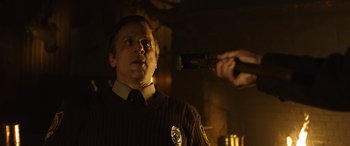 Movie still from “Wildling” (2018), directed by Fritz Böhm – A man in a police uniform is holding a gun; Close Up shot, Over the shoulder angle