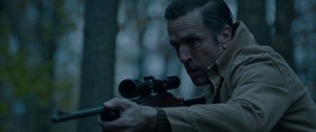 Movie still from “Wildling” (2018), directed by Fritz Böhm – A man is holding a rifle and aiming at something; Close Up shot, Over the shoulder angle