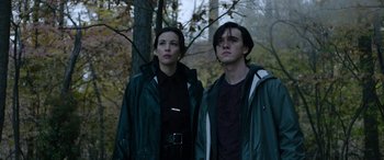 Movie still from “Wildling” (2018), directed by Fritz Böhm – A man and a woman standing next to each other in the woods; Medium shot, Low angle