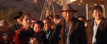Movie still from “Windtalkers” (2002), directed by John Woo – An older man and woman standing in front of a group of people; Medium shot, Over the shoulder angle