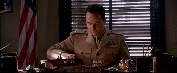 Movie still from “Windtalkers” (2002), directed by John Woo – A man in a military uniform sitting at a table; Medium shot, Low angle