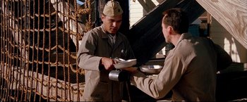 Movie still from “Windtalkers” (2002), directed by John Woo – A man handing a plate to another man holding it; Medium shot, Low angle