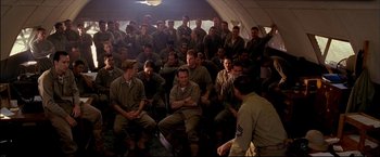 Movie still from “Windtalkers” (2002), directed by John Woo – A group of men sitting in a room with one man standing up; Wide shot, High angle