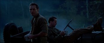Movie still from “Windtalkers” (2002), directed by John Woo – Two men are sitting in the dark with a gun; Medium shot, Low angle