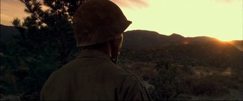 Movie still from “Windtalkers” (2002), directed by John Woo – A man wearing a helmet looking out at the sunset; Medium shot, Low angle