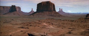 Movie still from “Windtalkers” (2002), directed by John Woo – Two people are standing on a dirt road in the desert; Extreme Wide shot, High angle