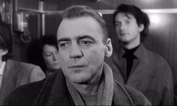 Movie still from “Wings of Desire” (1987), directed by Wim Wenders – Black and white photograph of a man in a crowd; Close Up shot, Low angle