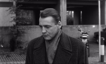 Movie still from “Wings of Desire” (1987), directed by Wim Wenders – Black and white photograph of a man in a coat; Close Up shot, Over the shoulder angle