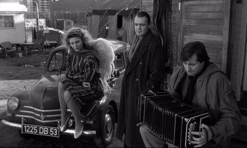 Movie still from “Wings of Desire” (1987), directed by Wim Wenders – A group of people standing next to each other near a car; Medium shot, High angle