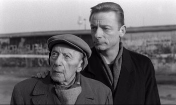 Movie still from “Wings of Desire” (1987), directed by Wim Wenders – An older man and a younger man standing next to each other; Close Up shot, Over the shoulder angle