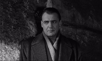 Movie still from “Wings of Desire” (1987), directed by Wim Wenders – Black and white photograph of a man wearing a coat; Close Up shot, Low angle