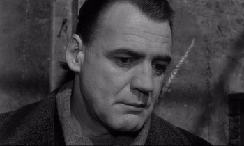Movie still from “Wings of Desire” (1987), directed by Wim Wenders – Black and white photograph of a man looking at the camera; Close Up shot, Low angle