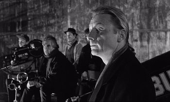 Movie still from “Wings of Desire” (1987), directed by Wim Wenders – A black and white photo of a group of people; Close Up shot, Over the shoulder angle