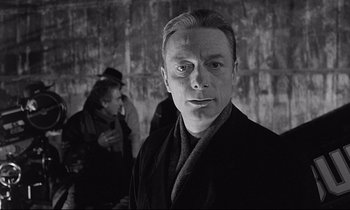 Movie still from “Wings of Desire” (1987), directed by Wim Wenders – Black and white photograph of a man in a robe; Close Up shot, Over the shoulder angle
