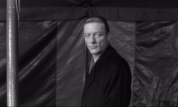 Movie still from “Wings of Desire” (1987), directed by Wim Wenders – Black and white photograph of a man wearing a suit; Close Up shot, Low angle
