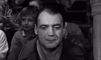 Movie still from “Wings of Desire” (1987), directed by Wim Wenders – A black and white photo of a man in a crowd of people; Close Up shot, Low angle