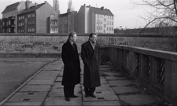 Movie still from “Wings of Desire” (1987), directed by Wim Wenders – A couple of men standing next to each other on a sidewalk; Wide shot, Low angle