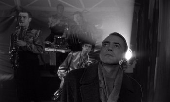 Movie still from “Wings of Desire” (1987), directed by Wim Wenders – A black - and - white photo of a man looking up; Close Up shot, Low angle