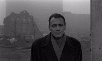 Movie still from “Wings of Desire” (1987), directed by Wim Wenders – A black and white photo of a man in a coat; Close Up shot, Low angle