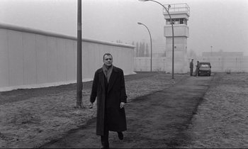 Movie still from “Wings of Desire” (1987), directed by Wim Wenders – A black and white photo of a man walking down a street; Wide shot, Low angle