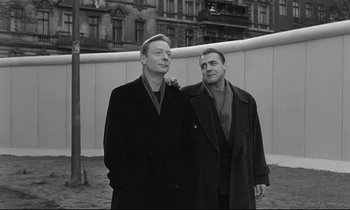 Movie still from “Wings of Desire” (1987), directed by Wim Wenders – A couple of men standing next to each other; Medium shot, Low angle