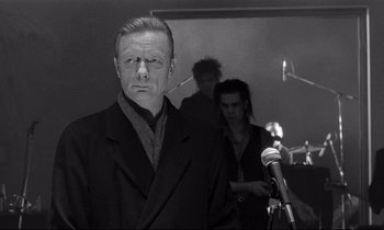 Movie still from “Wings of Desire” (1987), directed by Wim Wenders – Black and white photograph of a man in a suit; Medium shot, Over the shoulder angle