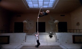 Movie still from “Wings of Desire” (1987), directed by Wim Wenders – A man and a woman are performing aerial acrobatics; Wide shot, Low angle