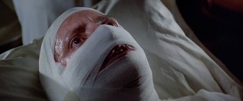 Movie still from “Winter Kills” (1979), directed by William Richert – A man with bandages on his head and face; Close Up shot, Low angle