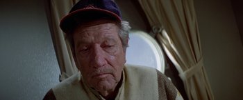 Movie still from “Winter Kills” (1979), directed by William Richert – An old man wearing a hat sitting in a chair; Close Up shot, High angle