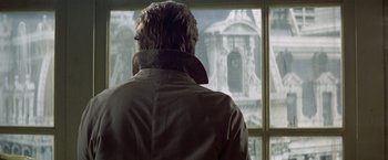 Movie still from “Winter Kills” (1979), directed by William Richert – A man standing in front of a window looking outside; Close Up shot, Over the shoulder angle