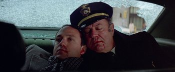 Movie still from “Winter Kills” (1979), directed by William Richert – Two men with fake blood on their faces; Close Up shot, High angle